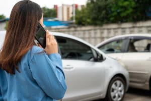Woman drivers call insurance after a car accident before taking pictures and sending insurance