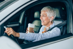 Women driving with headphones and coffee. 