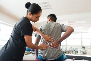 Medical professional examining patient's back.