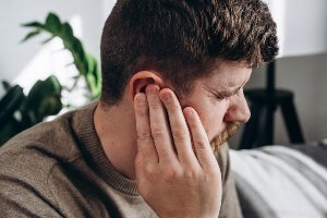 man with hand over ear