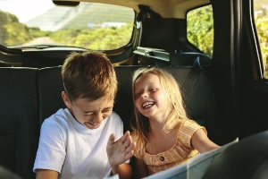 Children in a car backseat laughing.