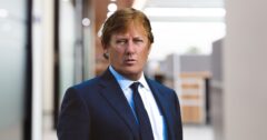 Headshot of Attorney Rusty Galloway wearing a navy suit with blurred office in background.